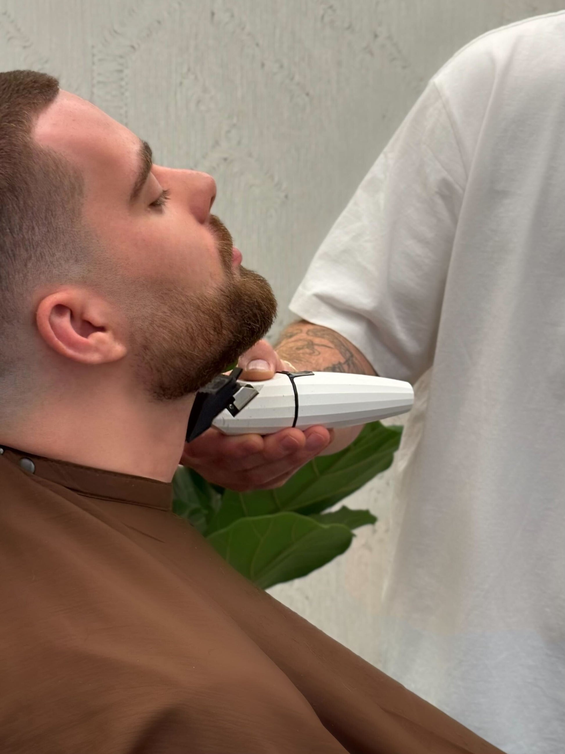 Man ondergaat professionele baardtrimming met tondeuse bij Sylvester Hair Studio in Velp – focus op strakke contourlijnen en verzorging.